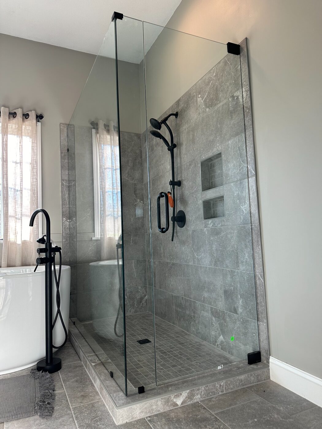 Frameless shower enclosure beside a tub