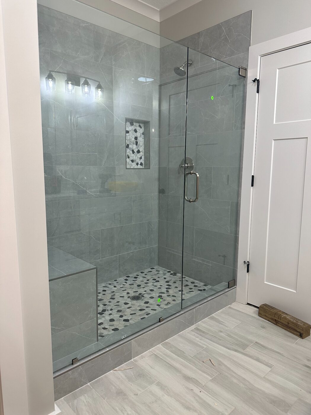 Frameless glass shower door with gray tile