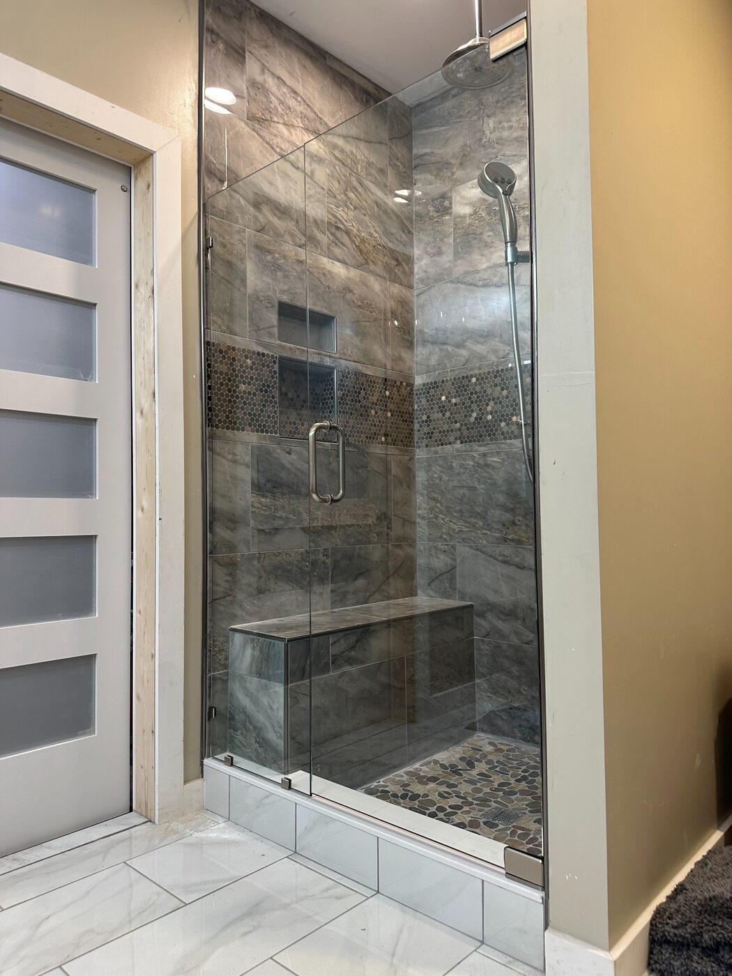 Frameless glass shower door with dark stone tile